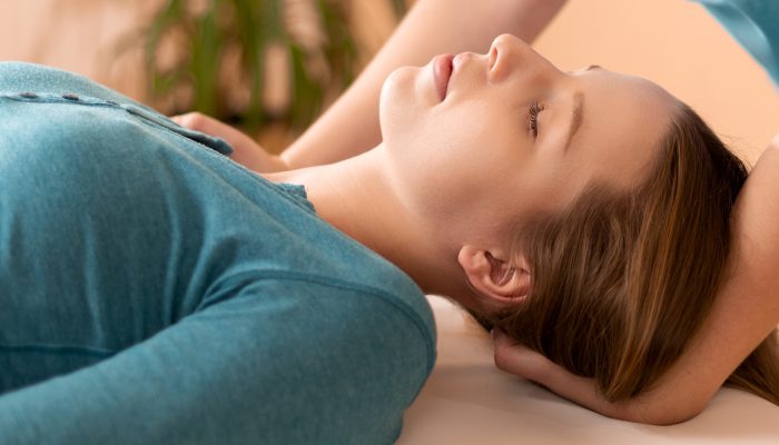 Female physiotherapist or a chiropractor adjusting patients neck. Physiotherapy, rehabilitation concept. Cropped shot banner.